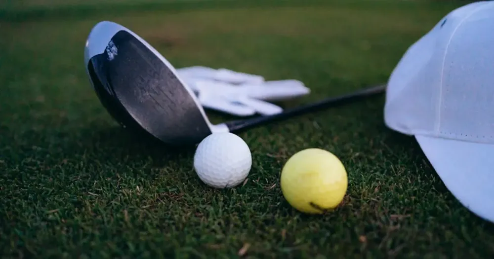 Close-up of golf club, balls, and cap on grass highlighting PGA Tour equipment and player updates.